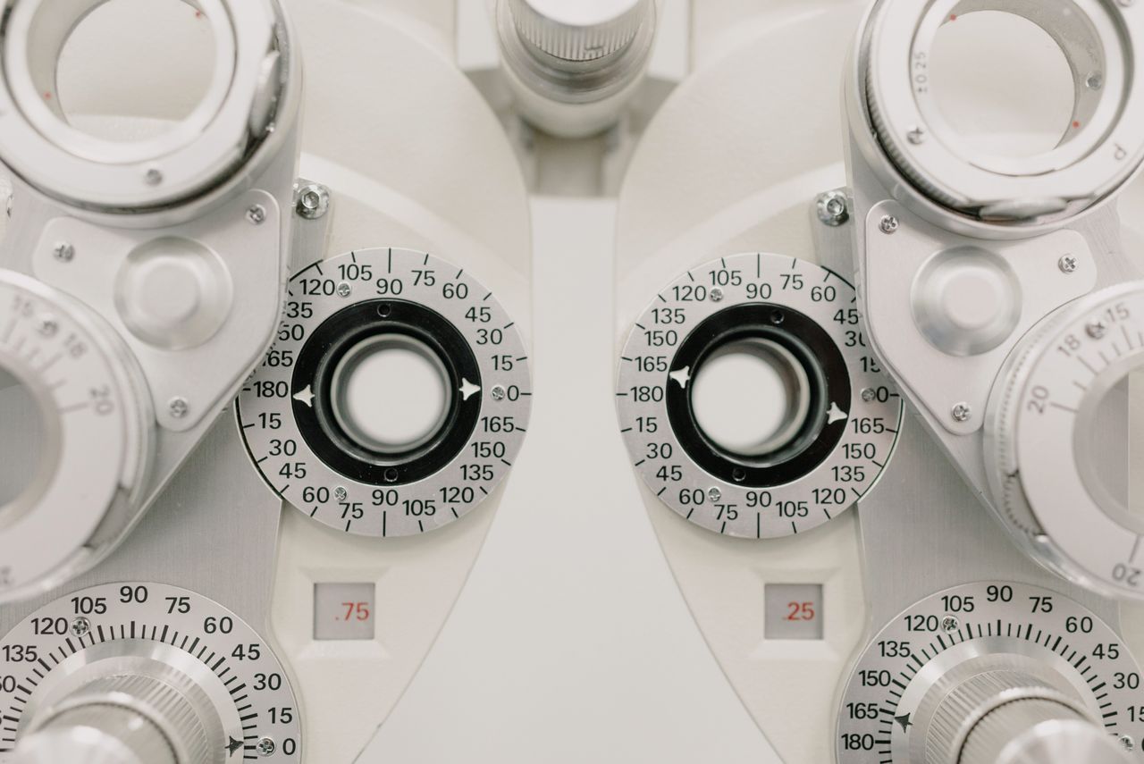 Modern white ophthalmic phoropter with optometric glasses for measuring eyesight made of metal placed on white background in contemporary clinic